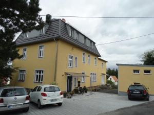 a yellow house with cars parked in front of it at Ferienwohnung Sonnenblick in Hohnstein