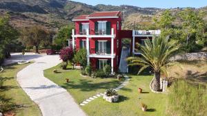 a red house with a palm tree and a road at Kykeon Studios in Katelios