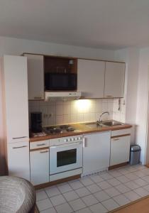 cocina con armarios blancos y fogones en Laboe-Appartement im Kapitänshaus, en Laboe