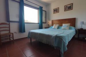 ein Schlafzimmer mit einem Bett mit blauen Vorhängen und einem Fenster in der Unterkunft Casa Kenya: Dúplex con azotea y magníficas vistas. in Rodalquilar