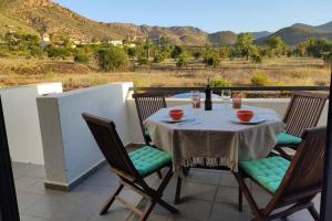 einen Tisch mit einer Flasche Wein und Stühlen auf dem Balkon in der Unterkunft Casa Kenya: Dúplex con azotea y magníficas vistas. in Rodalquilar