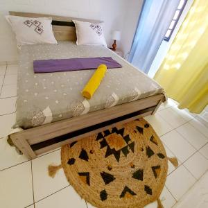 LÃCAZÈRĂ Sãfãrì في Mamoudzou: غرفة نوم مع سرير وسجادة على الأرض