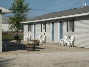 a white house with white chairs in front of it at White Caps Motel in Port Clinton