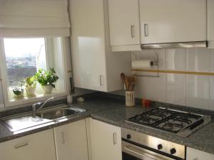 a kitchen with white cabinets and a sink and a window at Casa do Terraço in Aveiro +6 photos