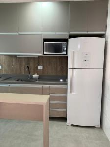a kitchen with a white refrigerator and a microwave at Fb HOME Guaruja- Apartamento proximo as praias da Enseada e Pitangueiras - WI FI in Guarujá