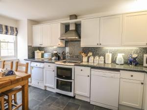 a kitchen with white cabinets and a stove top oven at Olde Carpenters Cottage in Boscastle