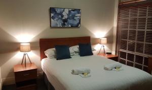 米塔贡Highlands Hotel的卧室里有一张白色的大床，床边还有两盏灯