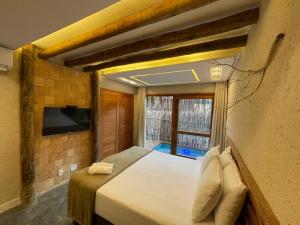 a bedroom with a large bed with a tv on the wall at Naim Milagres in São Miguel dos Milagres