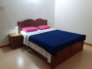 a bedroom with a bed with two pink pillows on it at Antonio's Residency Goa in Betalbatim