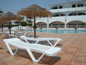 a group of chairs and umbrellas next to a pool at Baiona Club Villa 19 in Porches