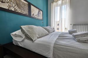 um quarto azul com uma cama com lençóis brancos e almofadas em Modern apt facing St Peter's and Vatican Museums - myPad in Rome em Roma