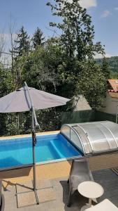 una sombrilla junto a una piscina con mesa y sillas en Onix- Kis-tó Apartman ORFŰ, en Orfű
