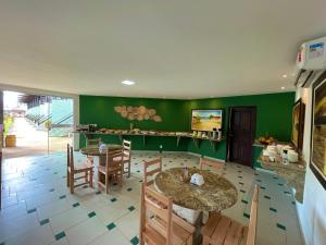 un comedor con 2 mesas y paredes verdes en MUTA PRAIA HOTEL en Porto Seguro