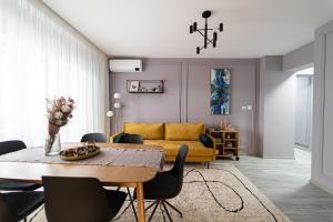 - un salon avec une table et un canapé jaune dans l'établissement Delux Suite, à Bacău