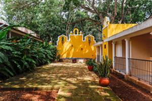 a yellow building with trees and plants in front of it at Hacienda San Miguel Yucatan in Valladolid