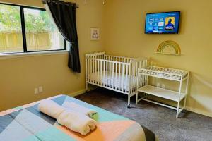 a bedroom with two cribs and a tv on the wall at Woodlands House - FREE Parking & Fast WiFi - 3 Bed. 1,5 Bath in The Woodlands