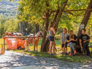 a group of people sitting on a bench next to a horse at Ninemia Stay and Play in Karpenisi