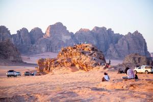 a group of people sitting on a rock in the desert at Arena Desert Camp & Adventurers in Wadi Rum