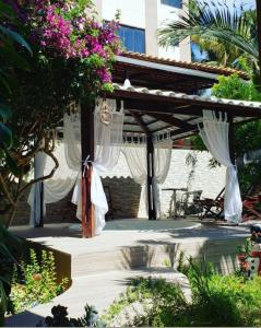 巴哈多昆堯的住宿－Pousada Mirante do Cunhaú，花园内带白色窗帘的木制凉棚