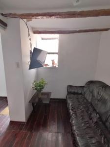 un soggiorno con divano in pelle e finestra di Asiriq Wasi Guest House a Cuzco