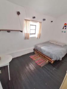 een slaapkamer met een bed, een tafel en een raam bij Asiriq Wasi Guest House in Cuzco
