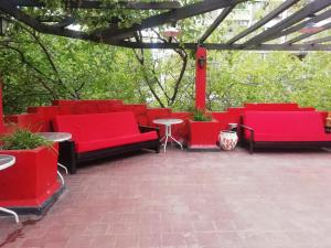 a group of red couches and tables on a patio at Katana Capsule Hostel in Mendoza