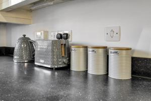 a row of cups sitting on a counter in a kitchen at Ruby Kingsize Bedroom with En-suite in Derby