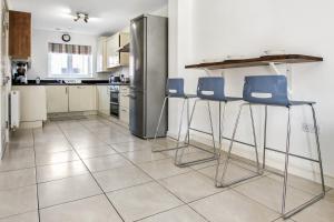 a kitchen with two bar stools and a stainless steel refrigerator at Ruby Kingsize Bedroom with En-suite in Derby