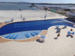 una gran piscina con sillas azules y una playa en Flat com praia privativa e lazer total em Arraial, en Arraial do Cabo