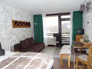 een slaapkamer met een bed, een bank en een raam bij Sweet Harmony Apartment mit Seeblick zum Genießen in Hahnenklee-Bockswiese