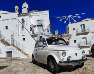 une voiture blanche garée devant un bâtiment blanc dans l'établissement Casa Isabella, à Monte SantʼAngelo