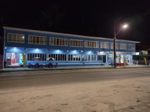 un edificio azul por la noche con una calle en Hotel Rainha, en Itapoa