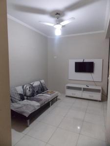 a living room with a bed and a flat screen tv at Apartamento Duplex Guarujá in Guarujá