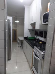 a kitchen with white cabinets and a stove top oven at Apartamento Duplex Guarujá in Guarujá