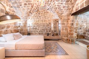 a bedroom with a bed and a stone wall at Zidan Sarai in ‘Akko