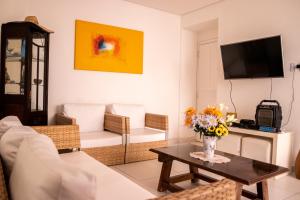 ein Wohnzimmer mit einer Blumenvase auf dem Tisch in der Unterkunft Apartamento com varanda Gourmet na praia da enseada in Guarujá