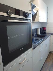 una cocina con horno negro y armarios blancos en Landruhe, en Strukkamp auf Fehmarn