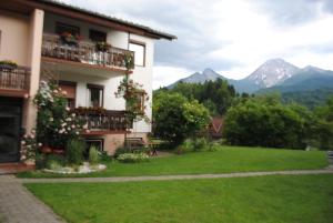 a building with a green yard with mountains in the background at Ferienhaus Michor in Latschach ober dem Faakersee