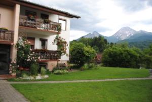 un edificio con un cortile verde con montagne sullo sfondo di Ferienhaus Michor a Latschach ober dem Faakersee