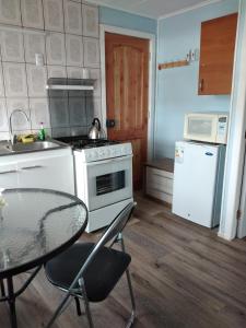 eine Küche mit einem Tisch, einem Herd und einem Kühlschrank in der Unterkunft Cabañas Campestres Las Rosas in Punta Arenas
