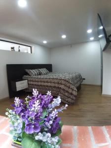 a bedroom with a bed and a vase of purple flowers at Hermoso apartamento con vista al lago in Paipa