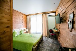 Hyde Park Resort Bishkek2023 في بيشكيك: غرفة في الفندق مع سرير أخضر ومكتب