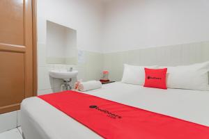 a red blanket on a white bed with a sink at RedDoorz @ Komplek Pontianak Mall in Pontianak