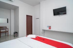 een witte kamer met een bed met een rode deken bij RedDoorz Syariah near Jalan Ahmad Yani Banjarmasin 3 in Sungai Lutus