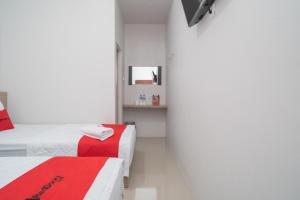 a white room with two beds and a red blanket at RedDoorz Syariah near Jalan Ahmad Yani Banjarmasin 3 in Sungai Lutus
