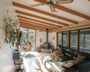a woman sitting on a couch in a living room at Glenaire Cottages in Glenaire
