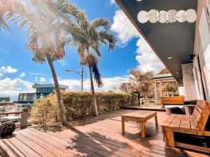 een houten terras met palmbomen en een bank bij Green Island 9 Padi in Green Island