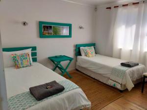 ein Zimmer mit zwei Betten und einem Tisch darin in der Unterkunft Cottage Amnesia in Bettyʼs Bay