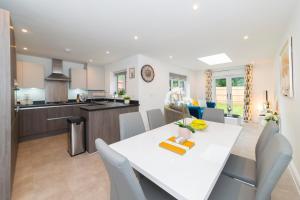a kitchen and living room with a white table and chairs at Greenfields's Hurley House - New modern 4 Bedroom House in Bracknell