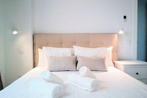 Una cama blanca con dos toallas plegables. en Top-notch downtown house with private rooftop terrace and parking opt en Sevilla